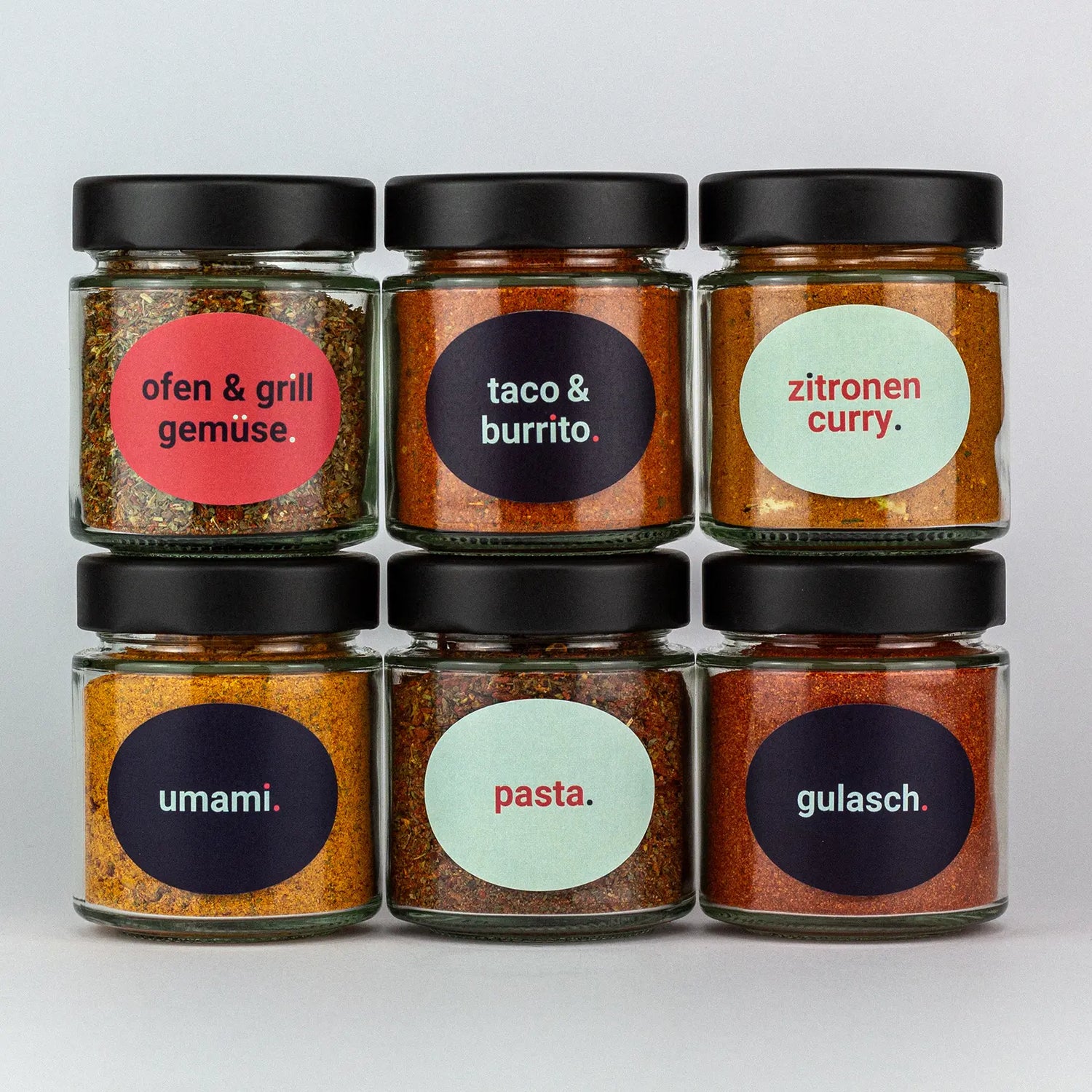 Die Gewürze des Gewürzmischungen Set Ofen Grillgemüse, Taco und Burrito, Zitronencurry, Umami, Pasta und Gulasch in Gläsern aufeinandergestapelt.