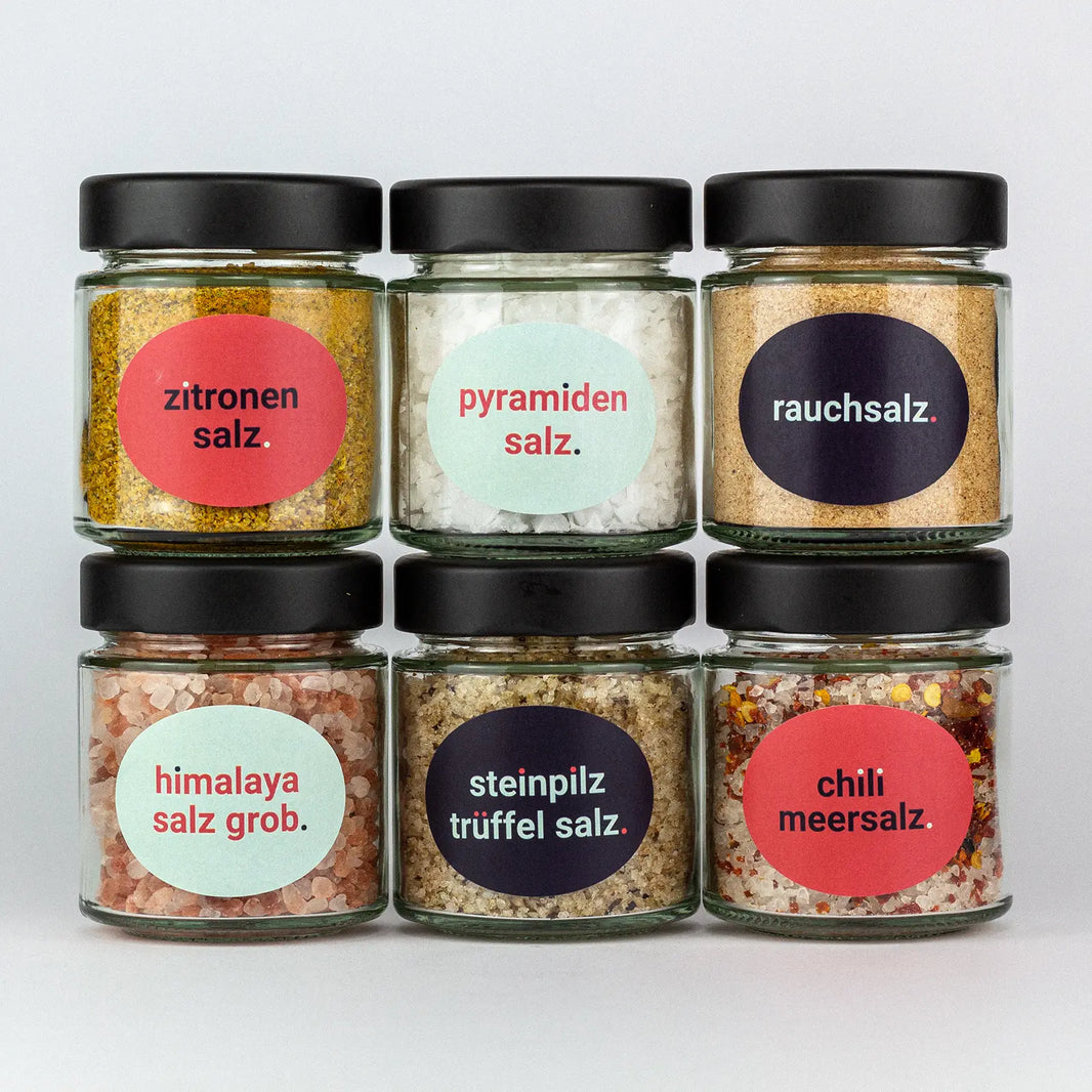Die Gewürze des Salz Set Italienische Zitronensalz, Pyramidensalz, Rauchsalz, Himalaya Grob, Steinpilz Trüffel Salz und Chili Meersalz in Gläsern aufeinandergestapelt.