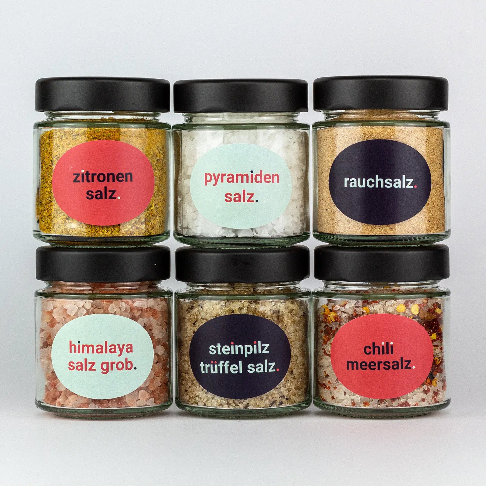 Die Gewürze des Salz Set Italienische Zitronensalz, Pyramidensalz, Rauchsalz, Himalaya Grob, Steinpilz Trüffel Salz und Chili Meersalz in Gläsern aufeinandergestapelt.